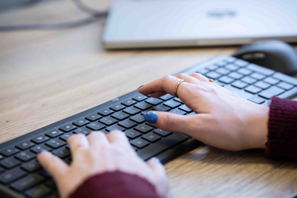 Vrouwenhanden typen op toetsenbord bij laptop