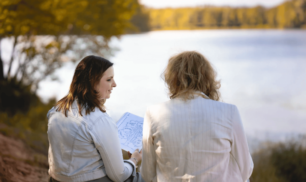 Twee vrouwen praten met kaart bij meer in bos.